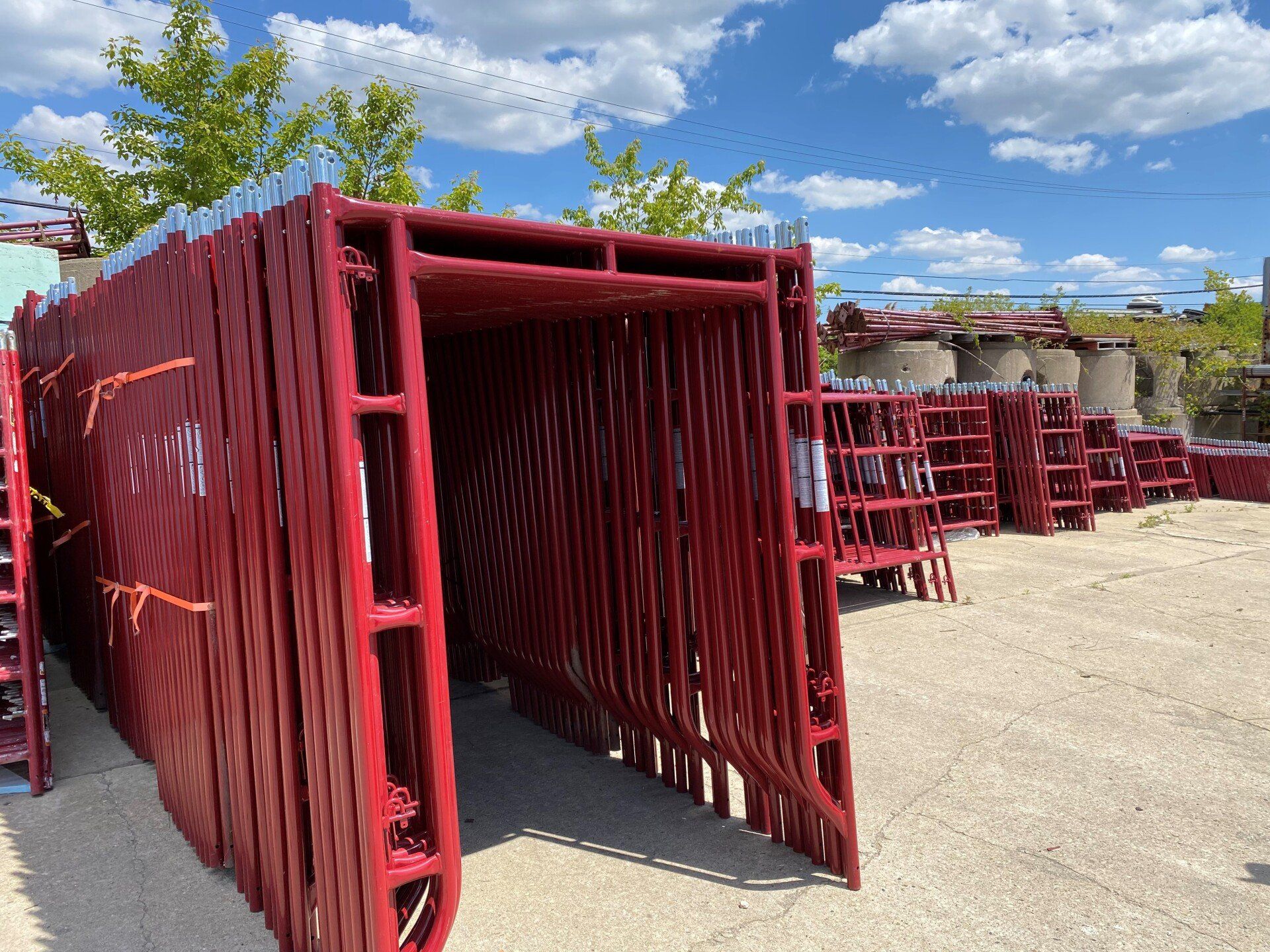 Stacks of red masonry wall braces stored outdoors, ready for commercial masonry construction projects