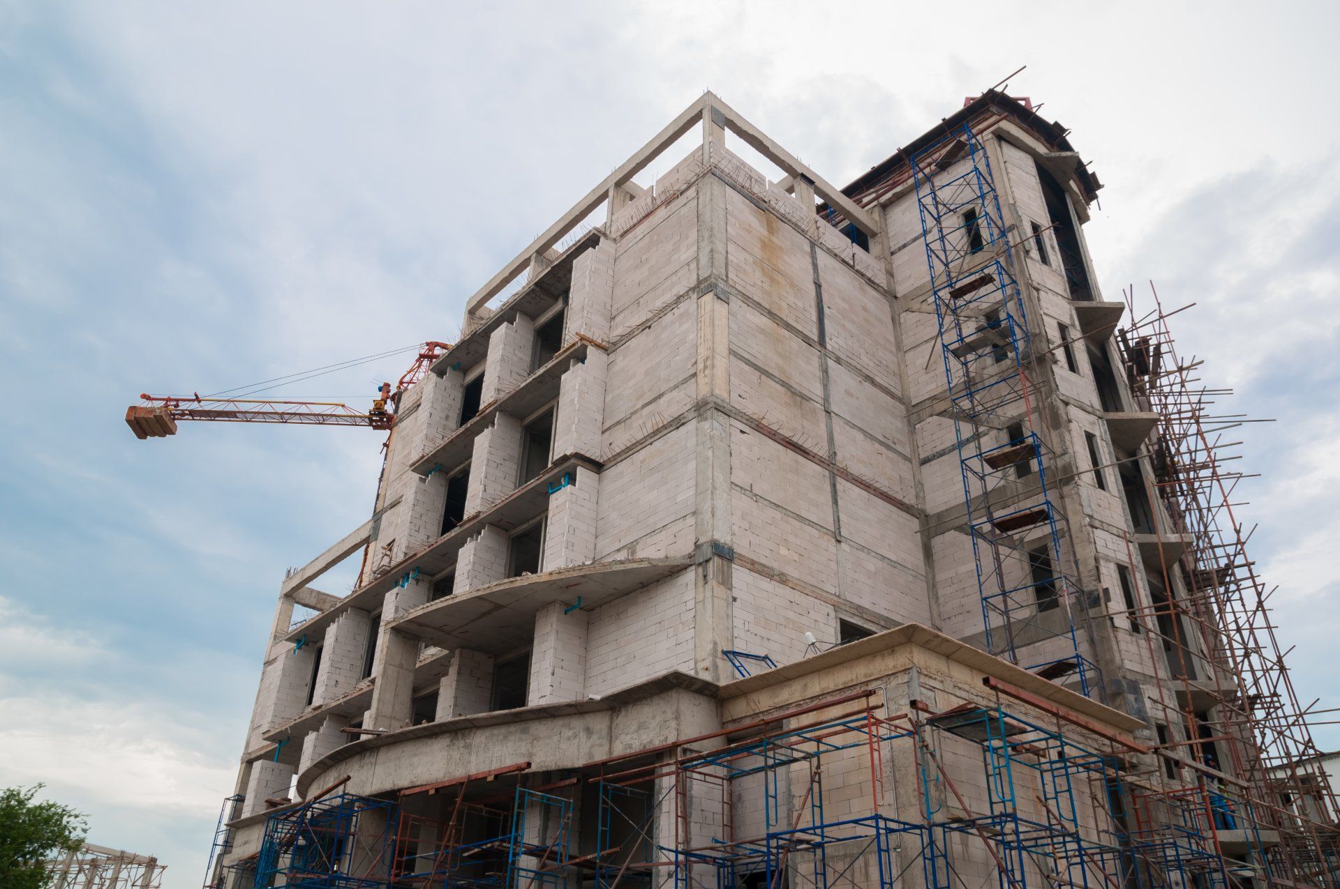 A multi-story building under construction with cranes and scaffolding surrounding it.