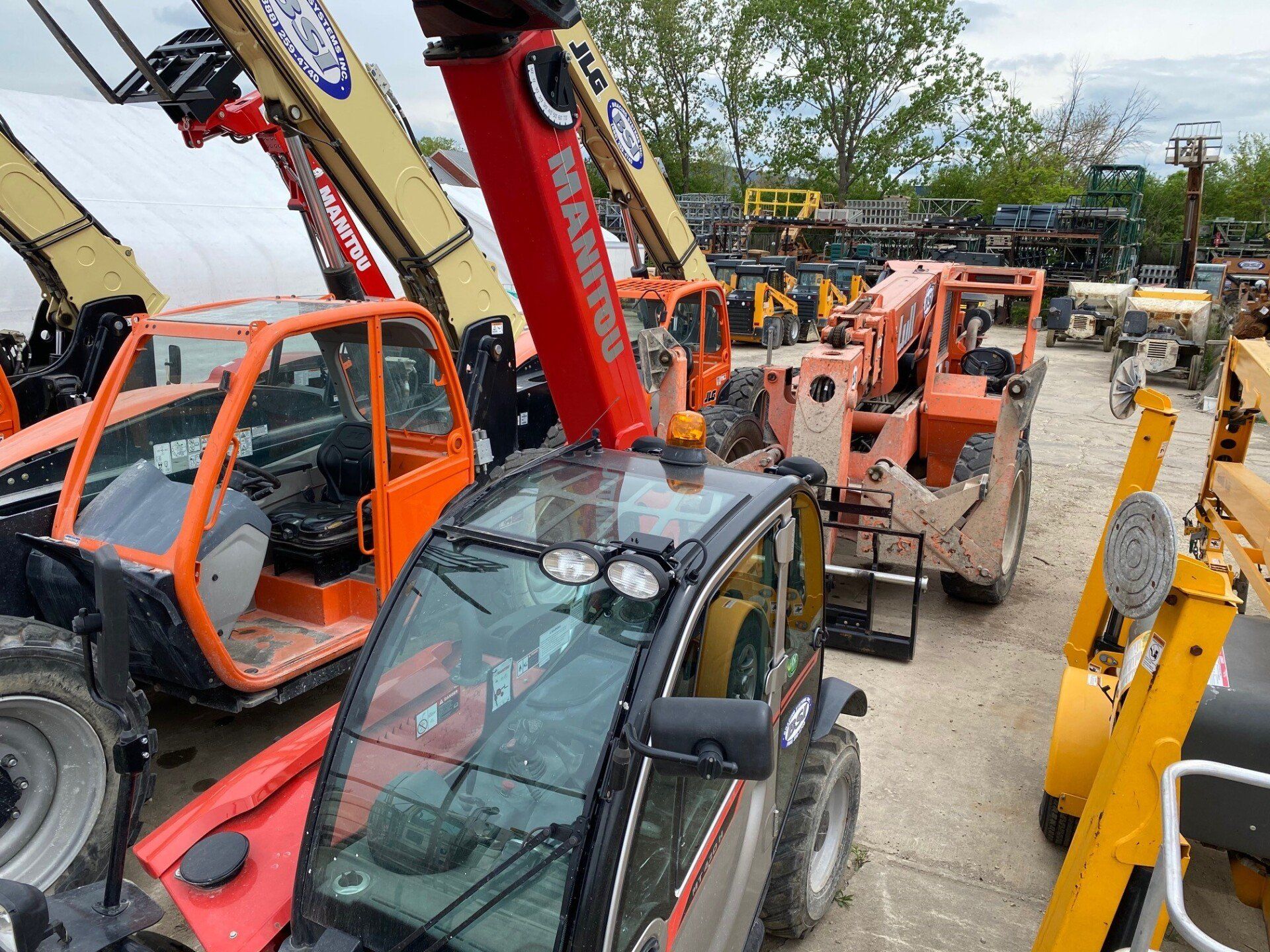 Telehandlers and rough terrain forklifts lined up at a construction equipment rental yard for masonry and concrete jobs