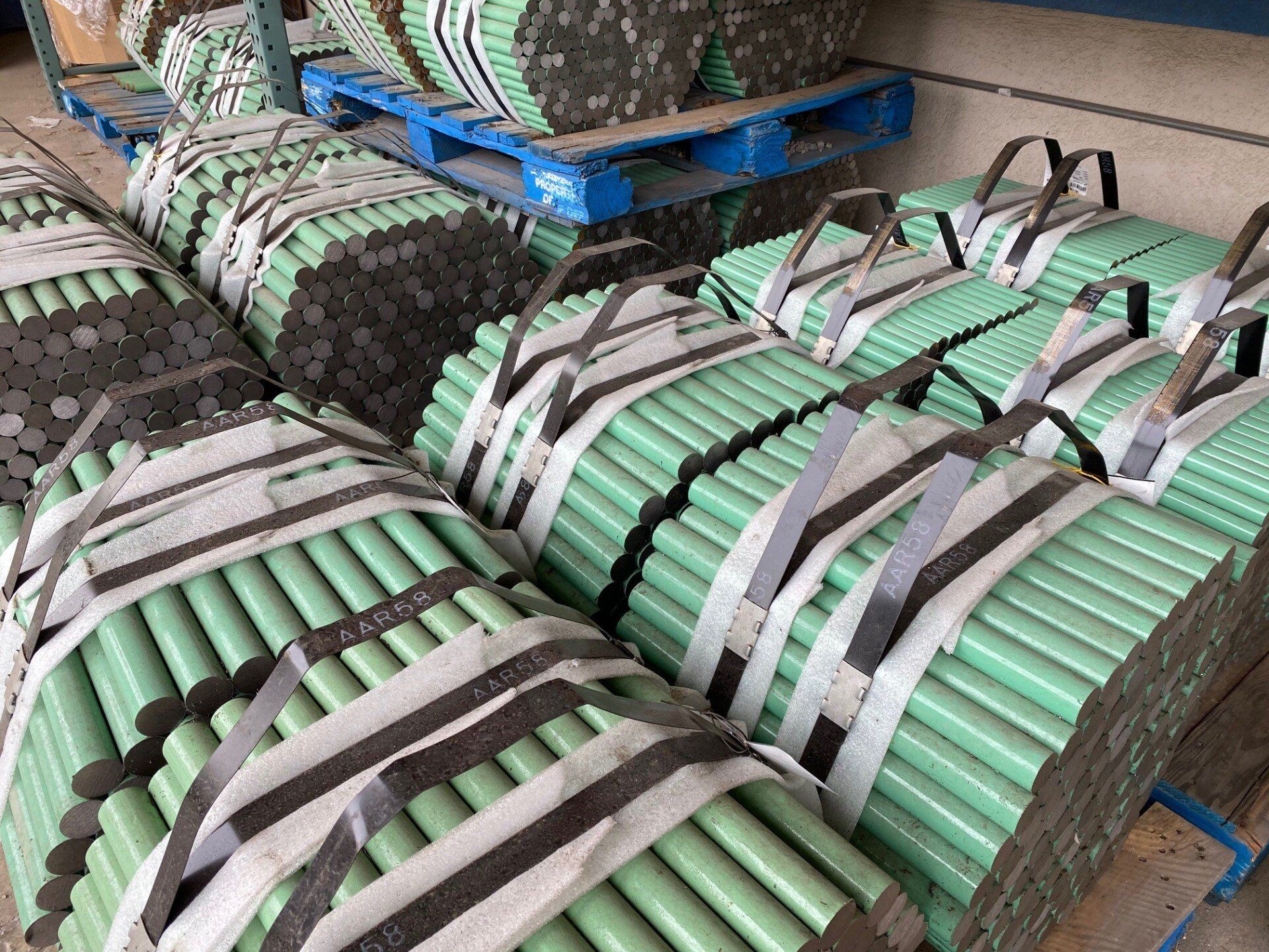Bundles of epoxy-coated concrete dowel bars stacked on pallets for concrete reinforcement applications