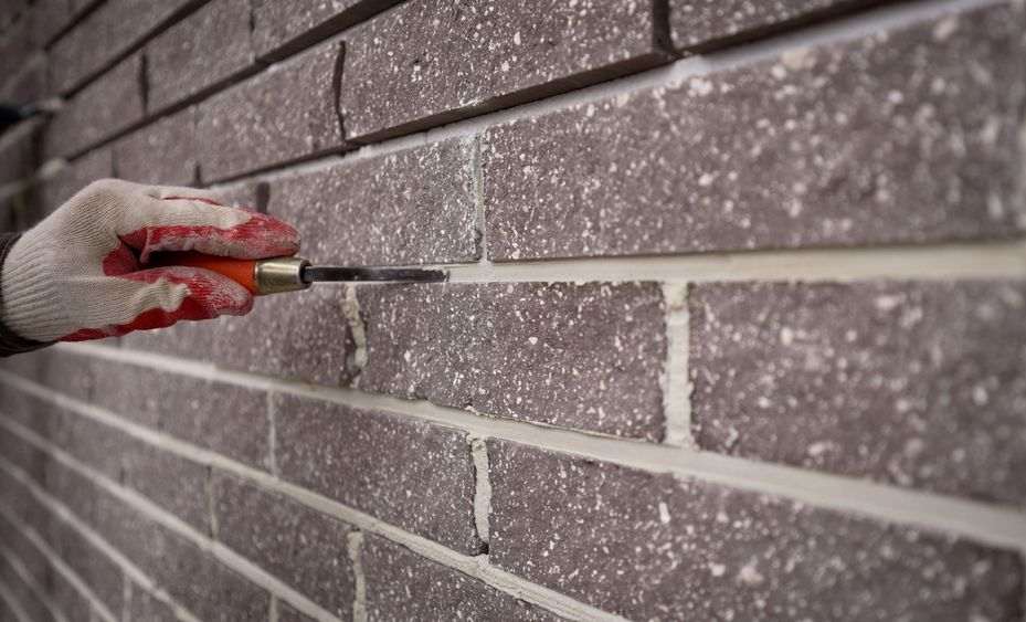 Worker wipes the seams in the brickwork. Worker rewrites a brick wall.