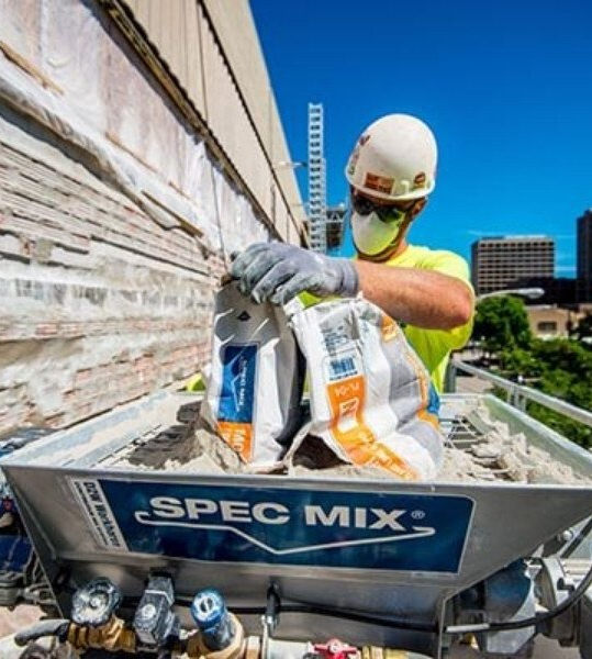 A concrete worker using a Spec Mix mortar mixer.