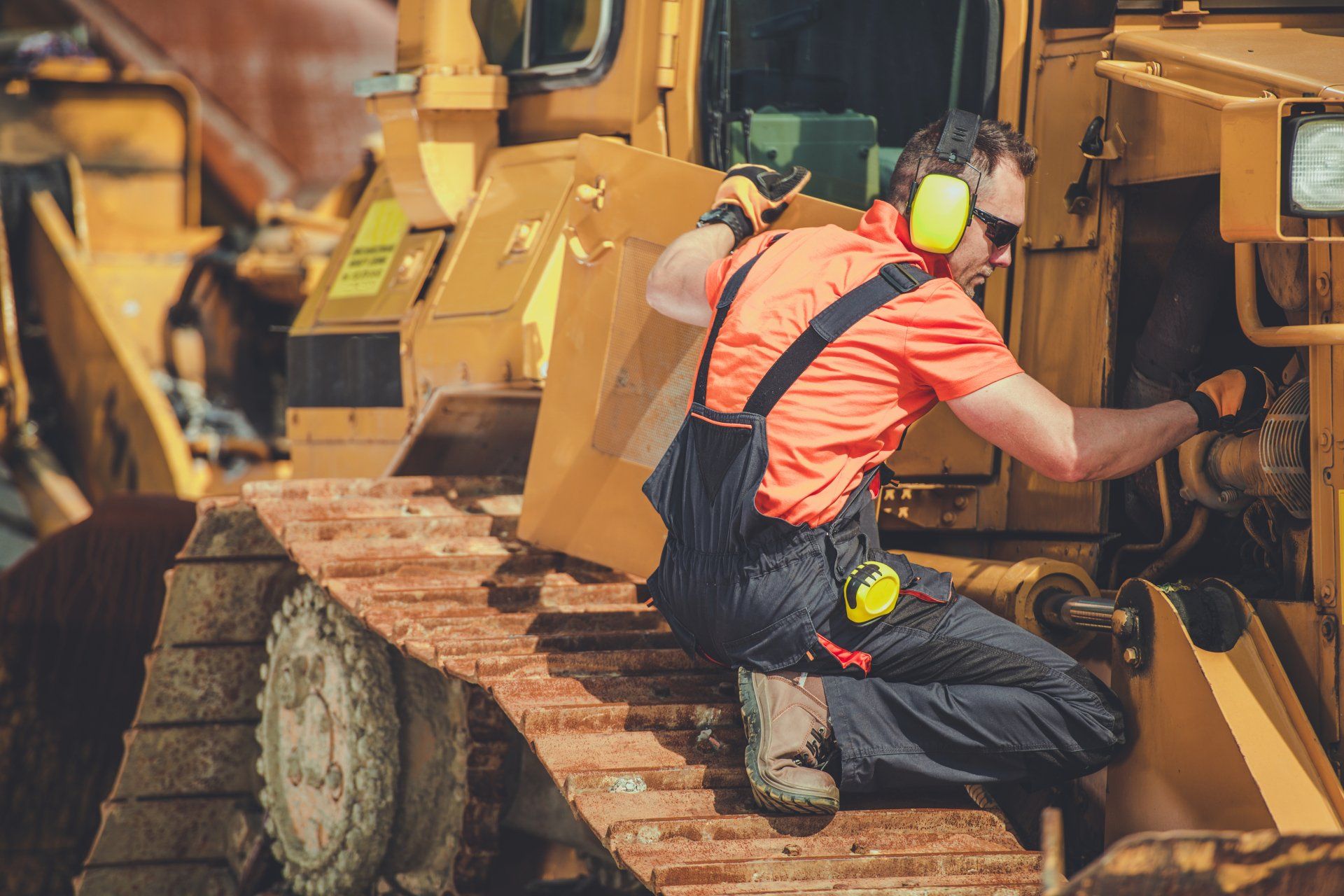 Technician performing maintenance on heavy construction equipment at jobsite.