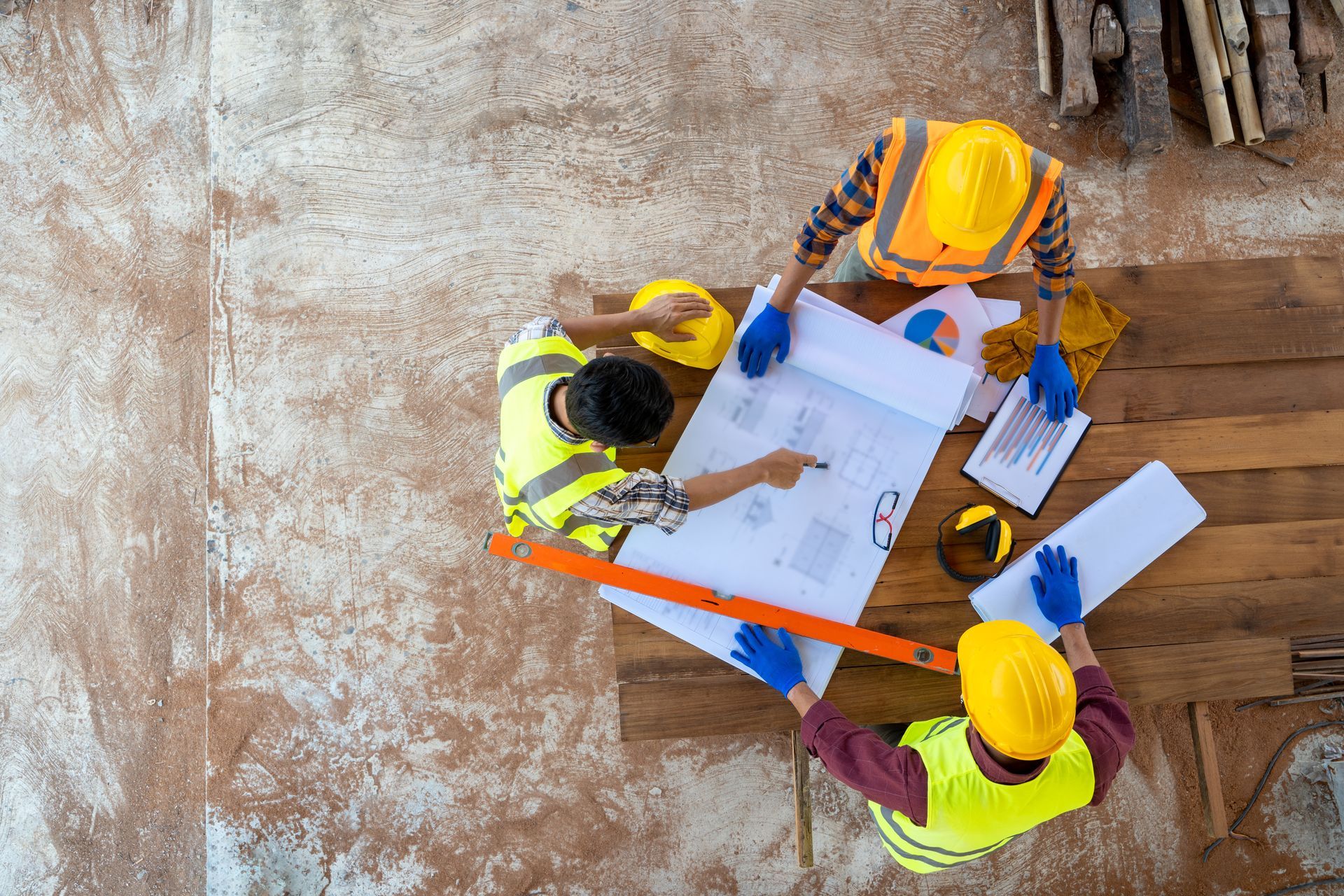 a group of construction workers are looking at a blueprint and discussing construction safety