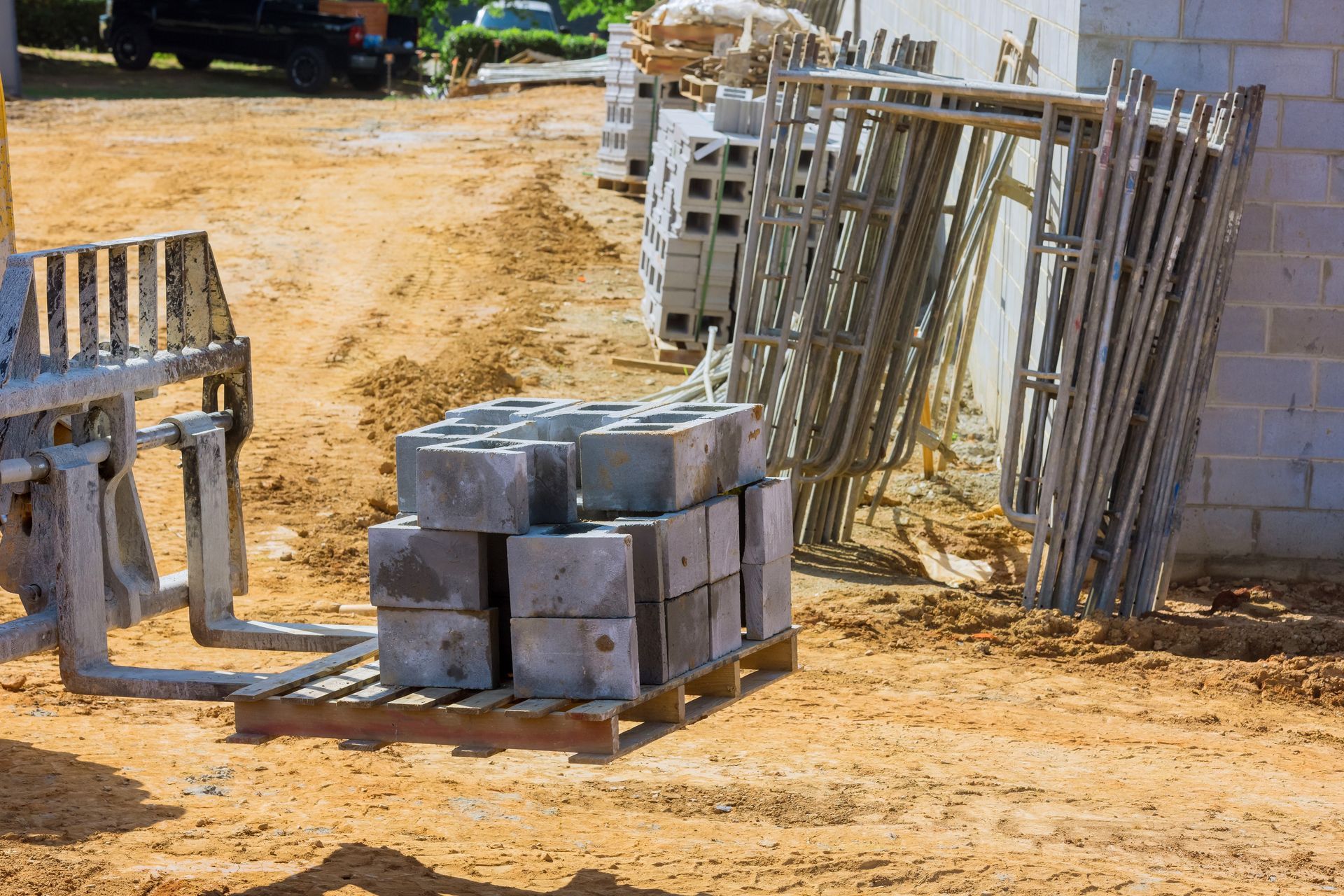 Masonry blocks on pallets with wall bracing and equipment staged at an active masonry construction site