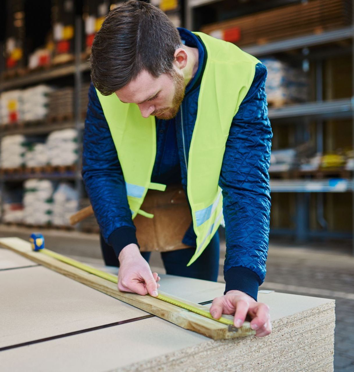The same young man is measuring a 1x2 from a local construction supplier