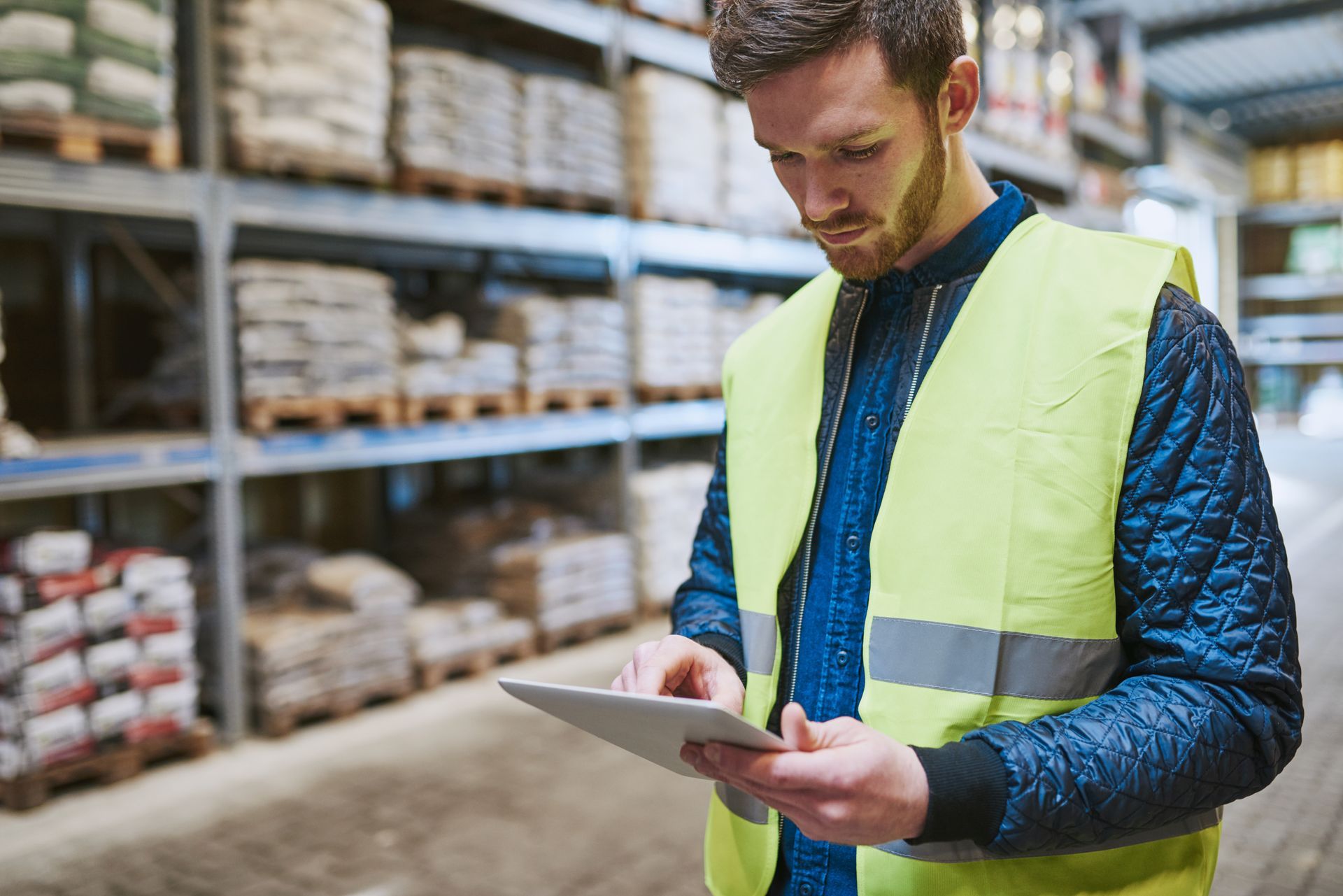 Young man looking up order details on a tablet as he shops in a hardware warehouse for local building materials | local construction supplies , close up upper body