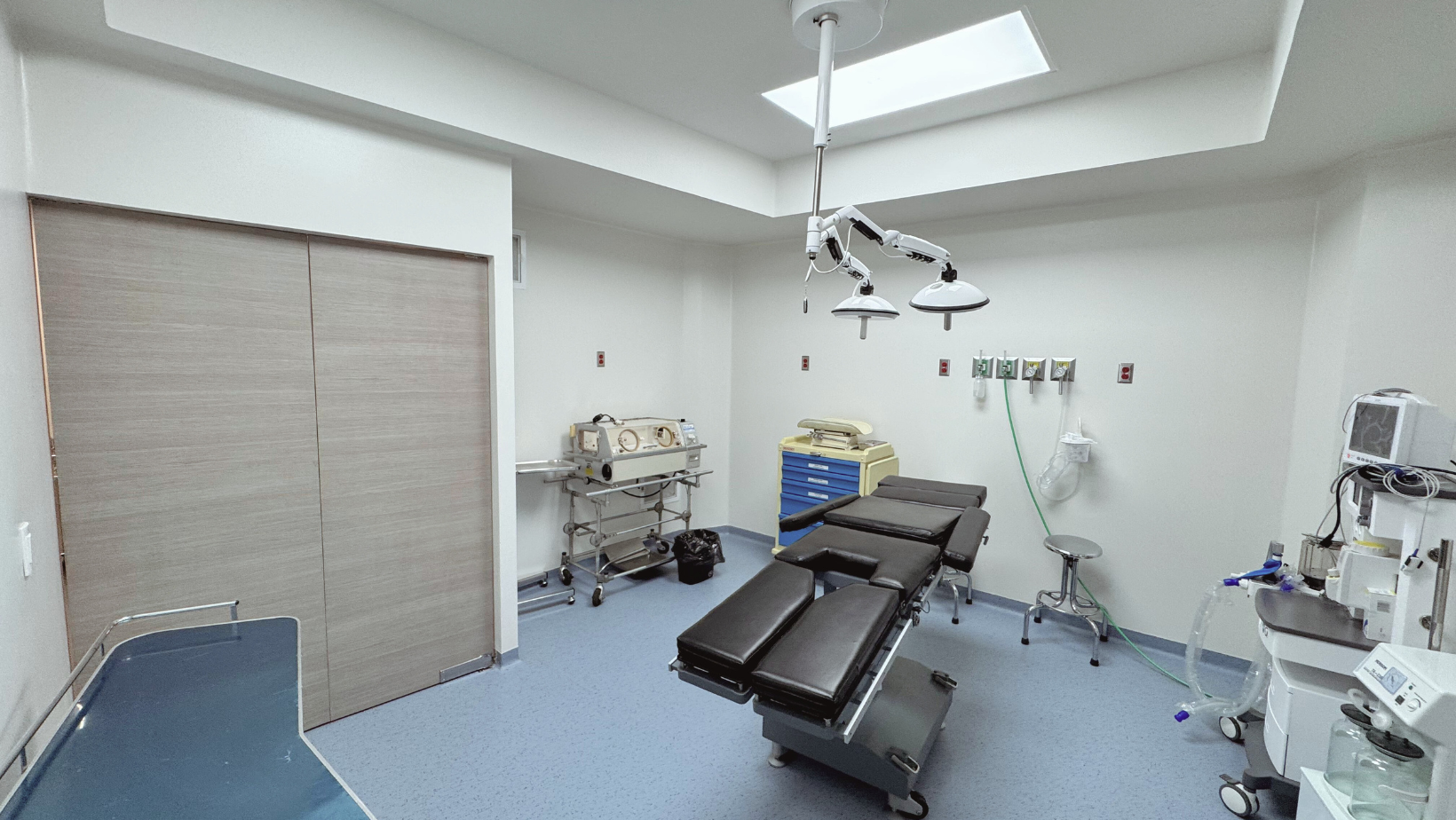 Una sala de operaciones vacía con mesa quirúrgica, equipo médico y una iluminación brillante en el techo.