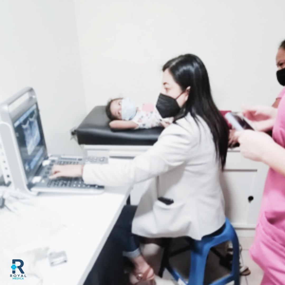 Un médico le realiza una ecografía a un bebé. Una enfermera está cerca. Entorno médico.