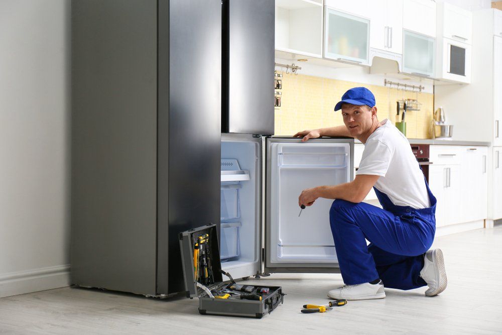 Male Technician With Screwdriver Repairing Refrigerator — Refrigeration & Air Conditioning in Jewells, NSW