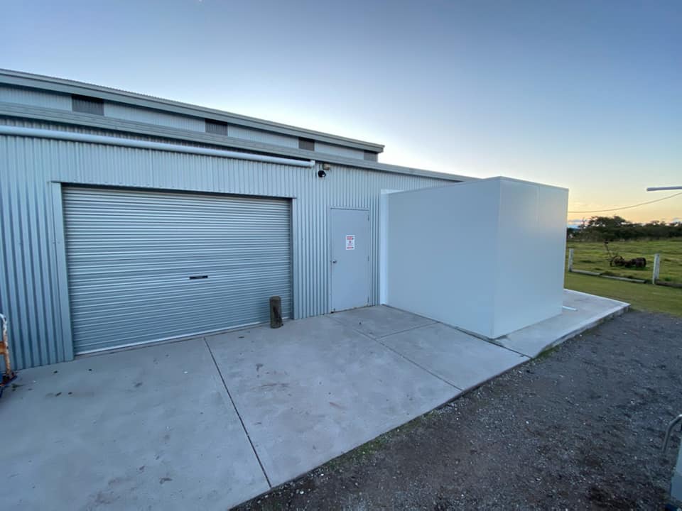 Exterior Of A Corrugated Metal Building With A Roll-up Door — Refrigeration & Air Conditioning in Jewells, NSW