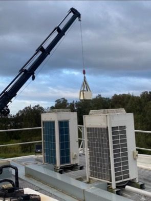 A Crane Lifts An Hvac Unit Onto A Rooftop — Refrigeration & Air Conditioning in Jewells, NSW