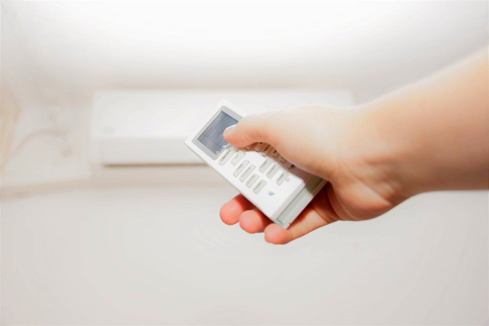 Female Hand Holds Airconditioning Remote — Refrigeration & Air Conditioning in Jewells, NSW