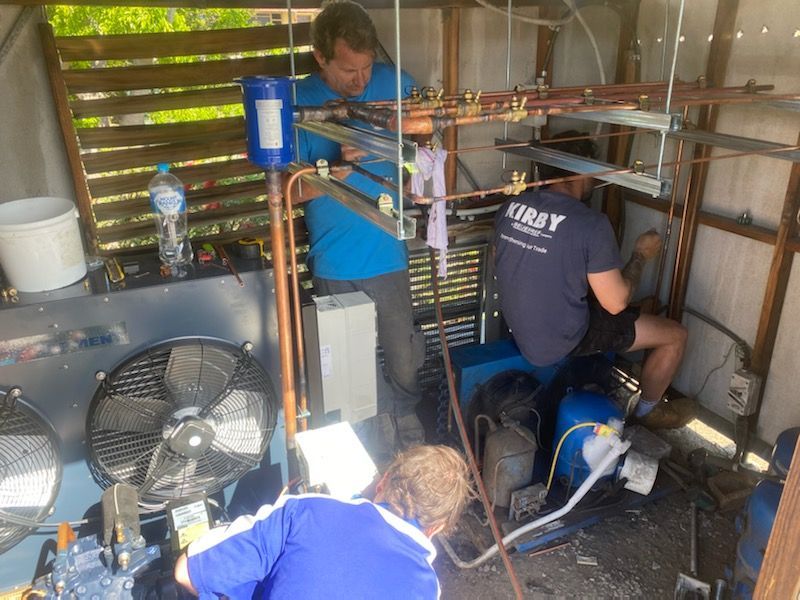 People Working in a Shed on a Cooling System — Refrigeration & Air Conditioning in Jewells, NSW