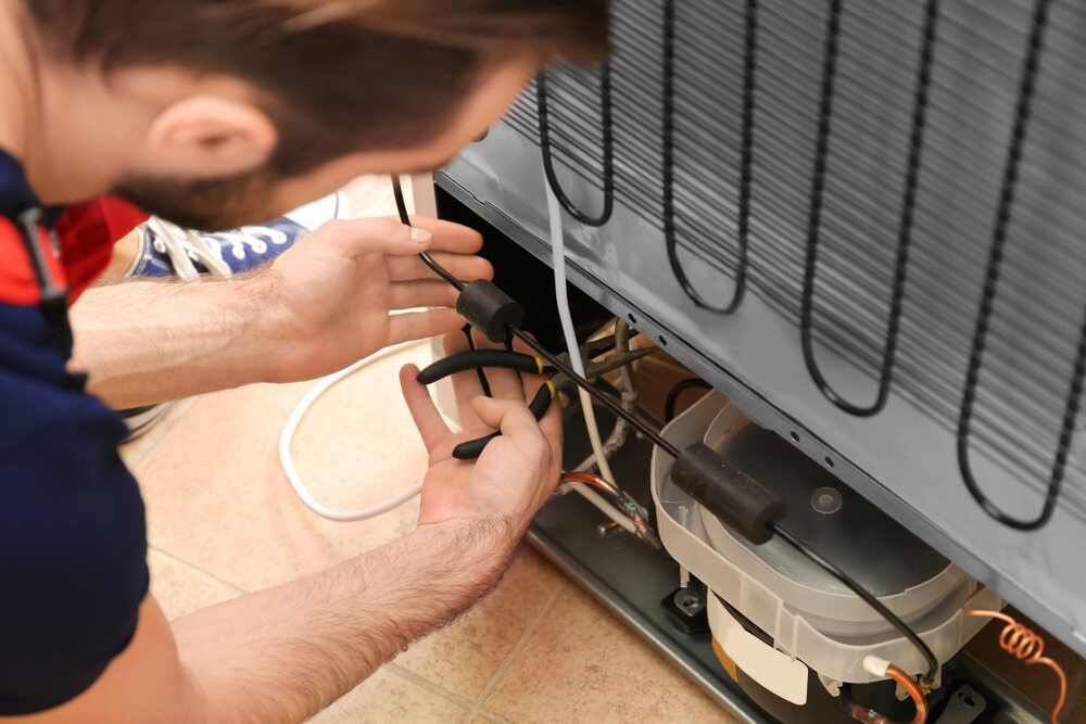Man Repairing a Refrigerator's Back, Using Tools on Wires — Refrigeration & Air Conditioning in Port Stephens, NSW