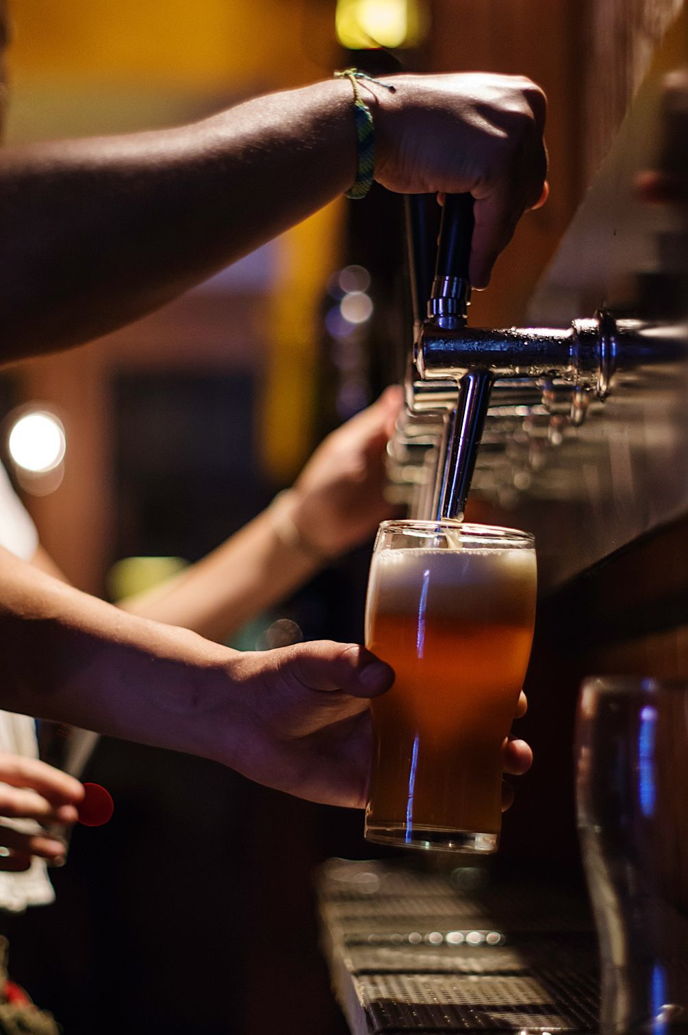 A Bartender Pouring Beer From A Tap Into A Pint Glass, Bar Setting — Refrigeration & Air Conditioning in Warners Bay, NSW