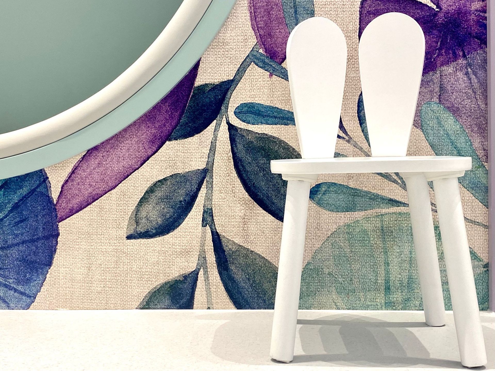 ein weißer Stuhl steht vor einer Wand mit einem Blumenmuster .