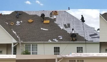 A group of people are working on a roof of a house.