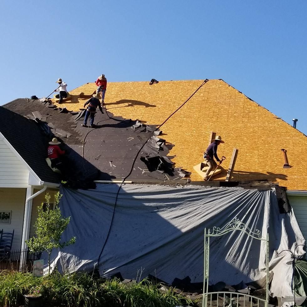 A group of people are working on the roof of a house