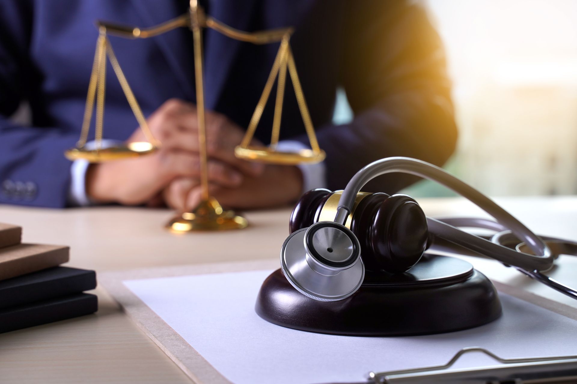A judge 's gavel and stethoscope are on a table in front of a scale of justice