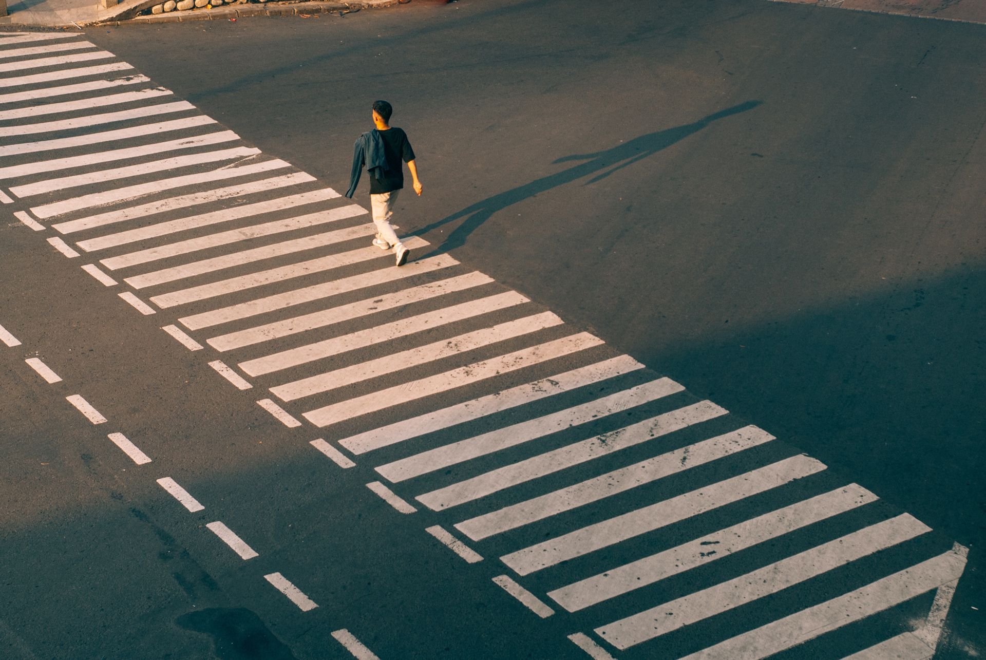 A person is walking across a crosswalk on a street