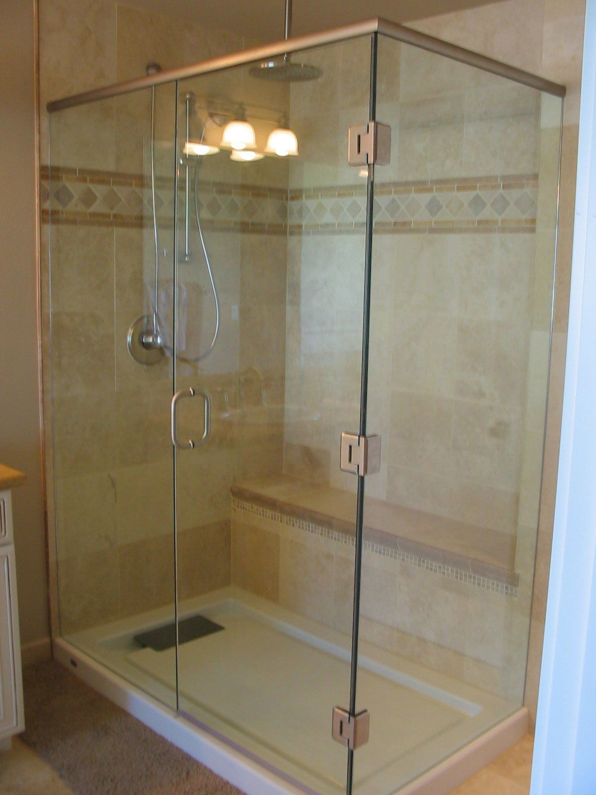 New Glass-enclosed shower stall with a built-in bench. Chrome fixtures and handle on the glass door.
