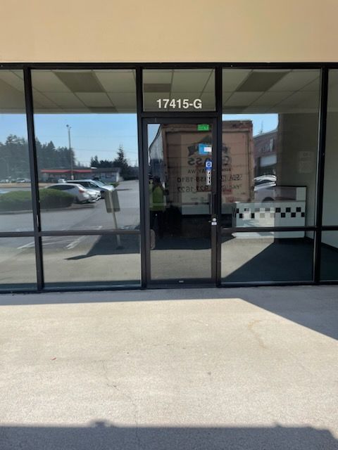 Exterior of a storefront with large windows and a door; address