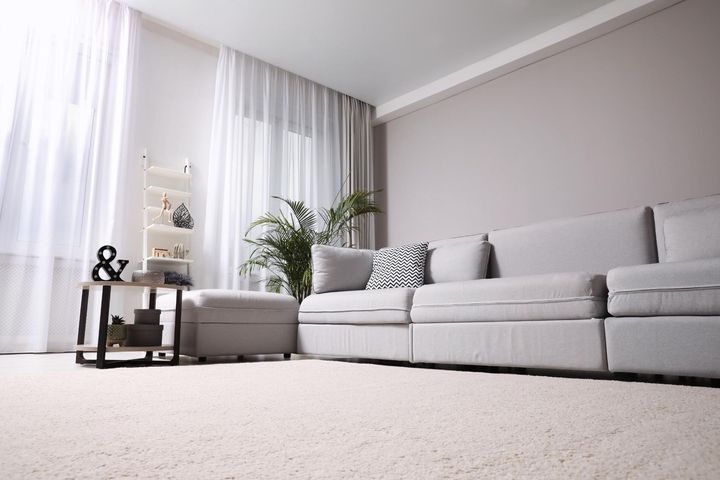 A living room with a couch, table, and curtains.