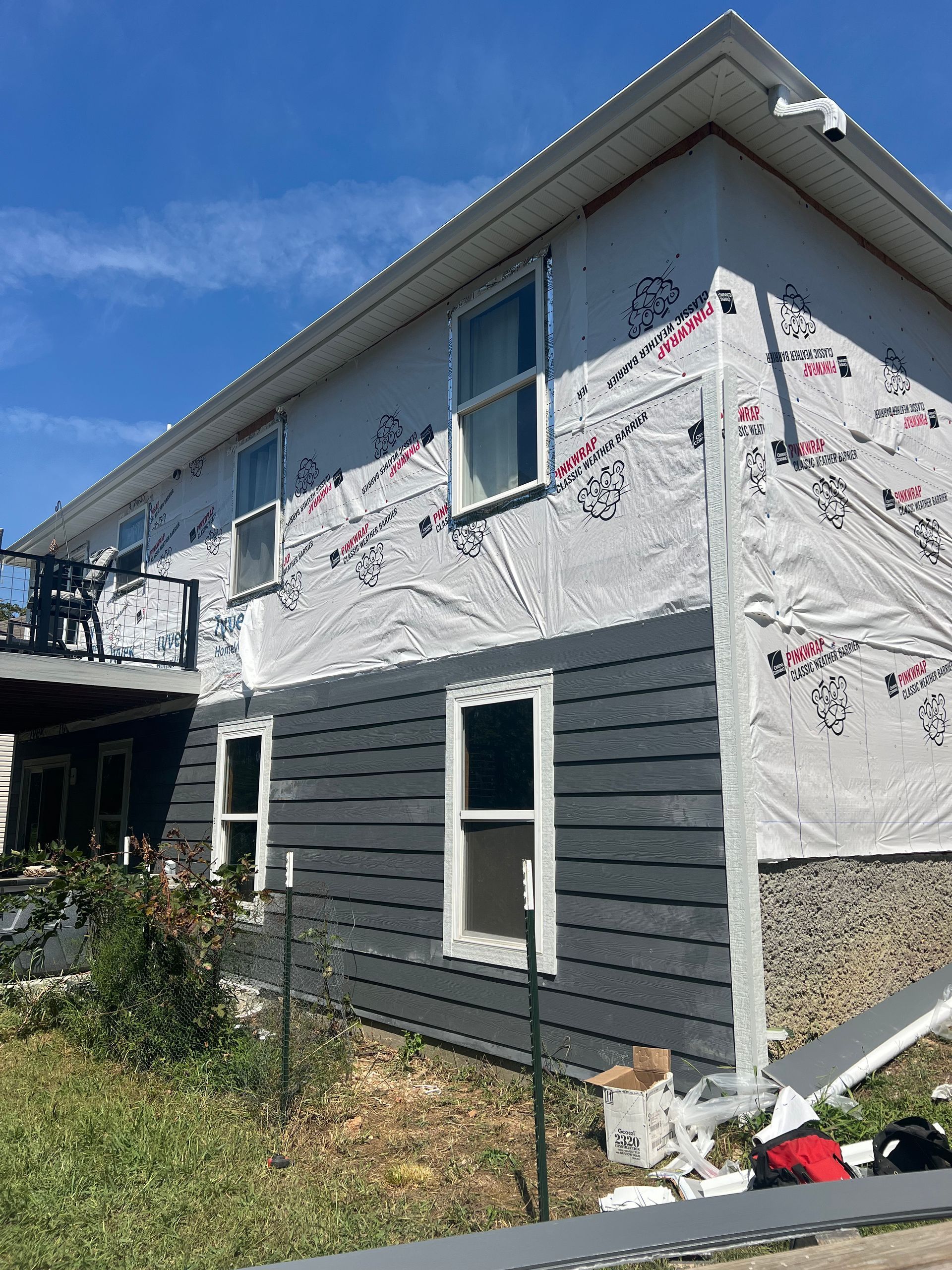 House roof replacement underway overlooking a lake; shingles and debris visible.