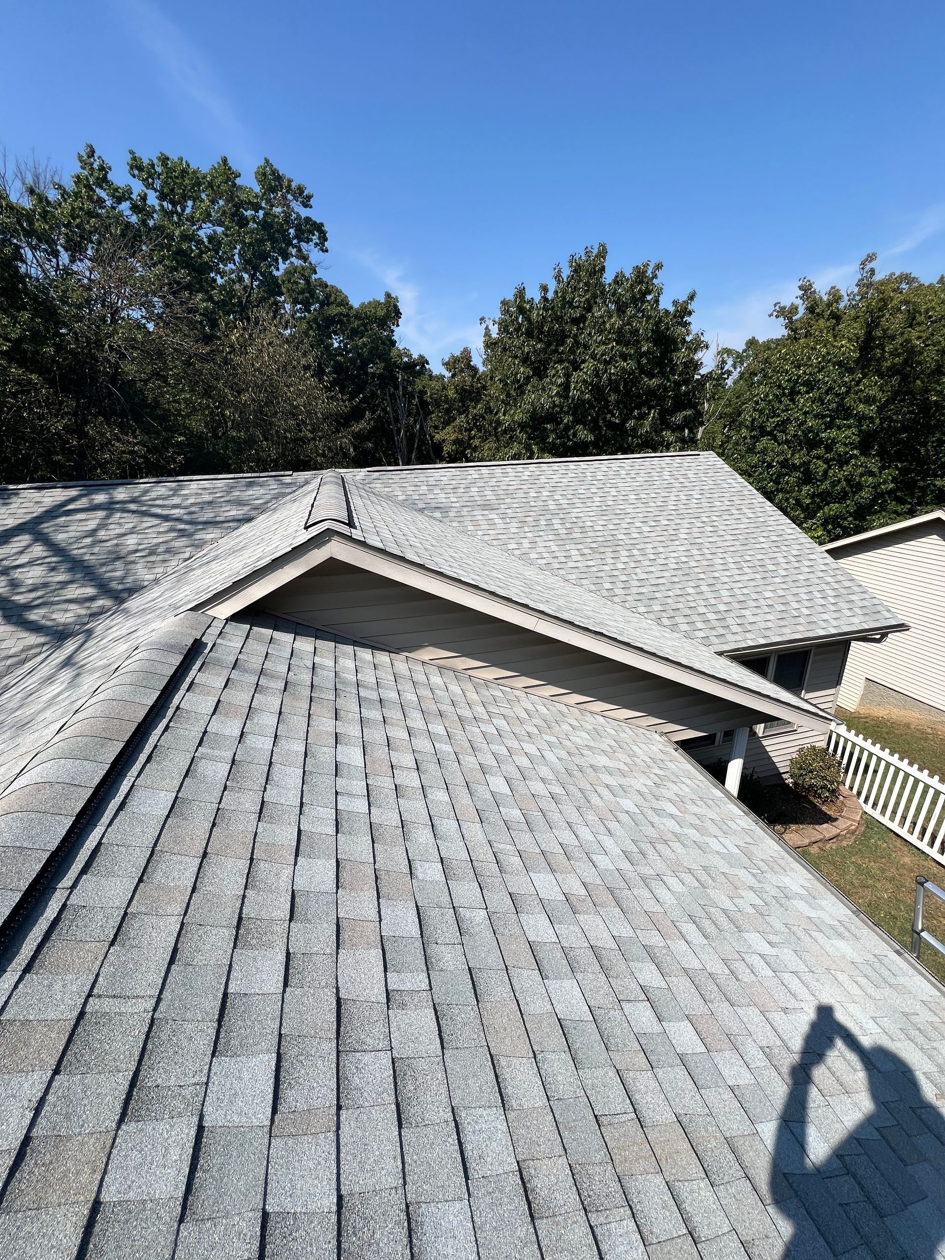 Black rain gutter on beige stucco wall beneath red tile roof against a blue sky.