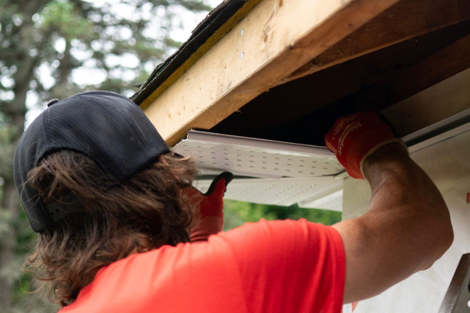 A professional contractor installing gutters on a residential home exterior
