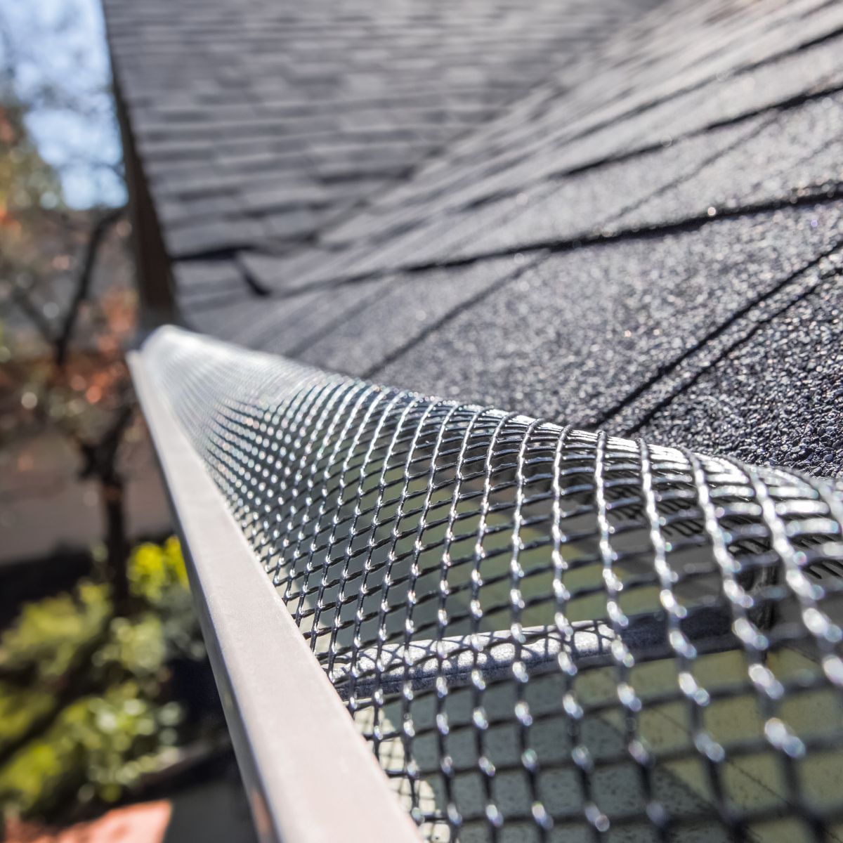 Gutter with mesh guard installed on a roof, protecting from debris.