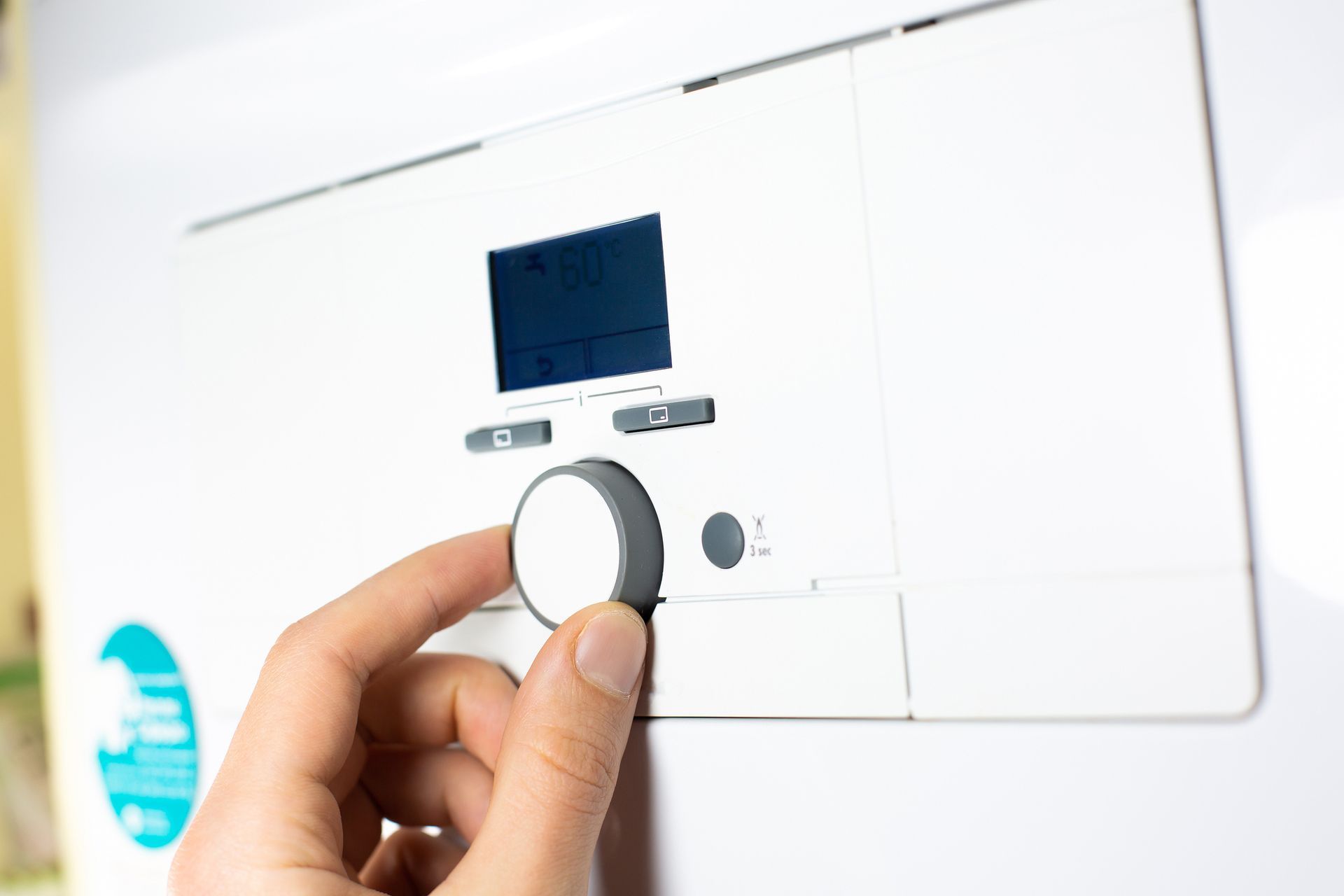 A person is adjusting a thermostat on a wall.