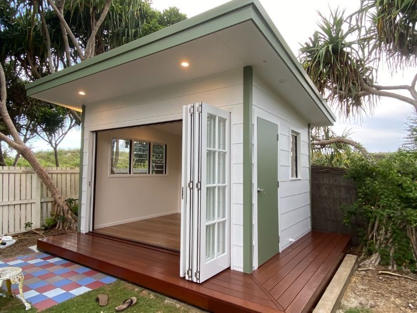 A Small White House With A Green Roof And A Wooden Deck — JC Coastal Construction In Coorabell, NSW