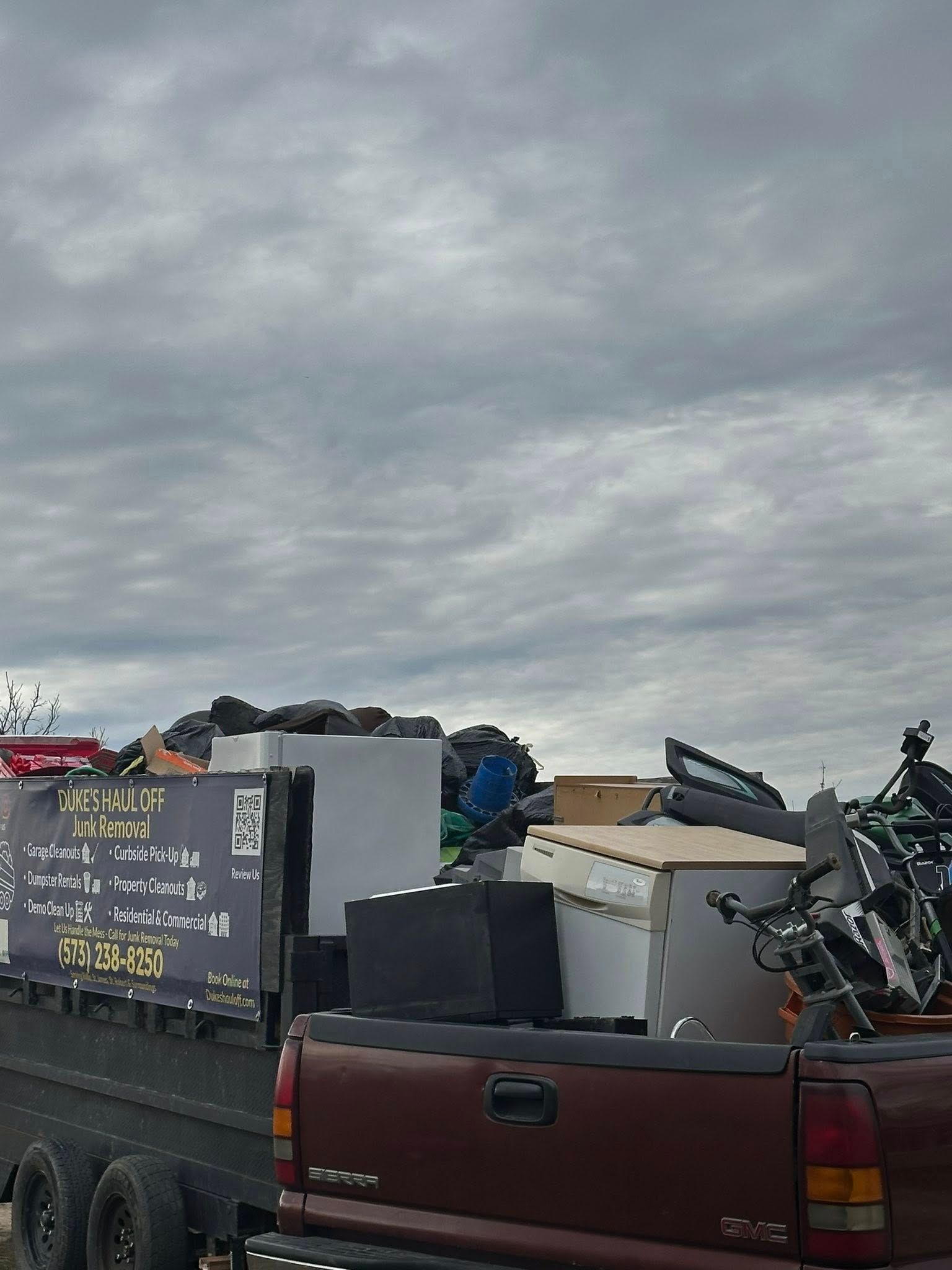 Pickup truck loaded with scrap metal and bins under a cloudy sky