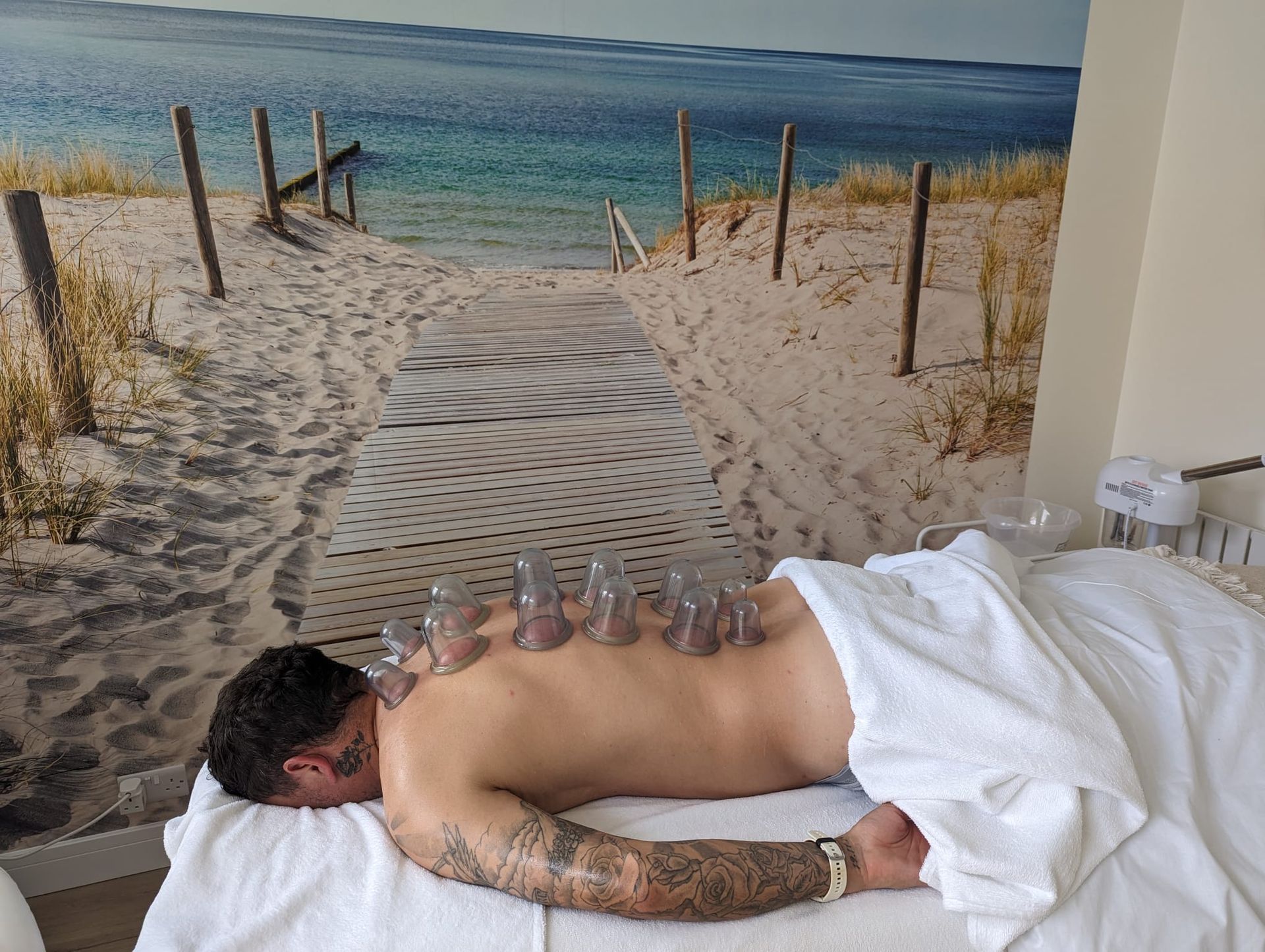 Person lying face down with cupping therapy on their back, in a spa-like setting.