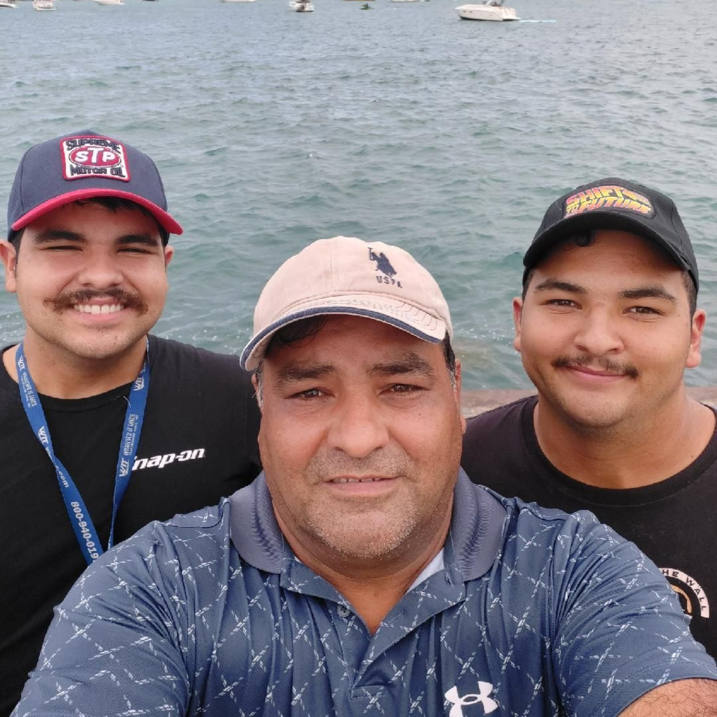 Three people smiling for a selfie on a boat with water in the background