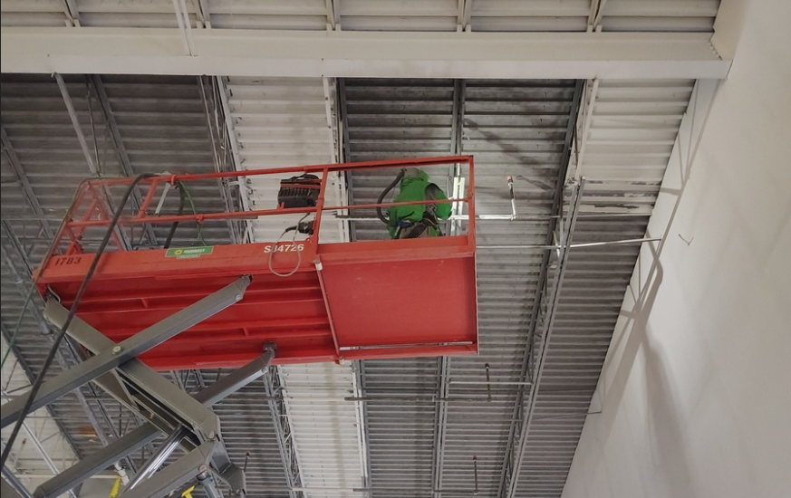 Professional painter on a lift painting interior of a warehouse