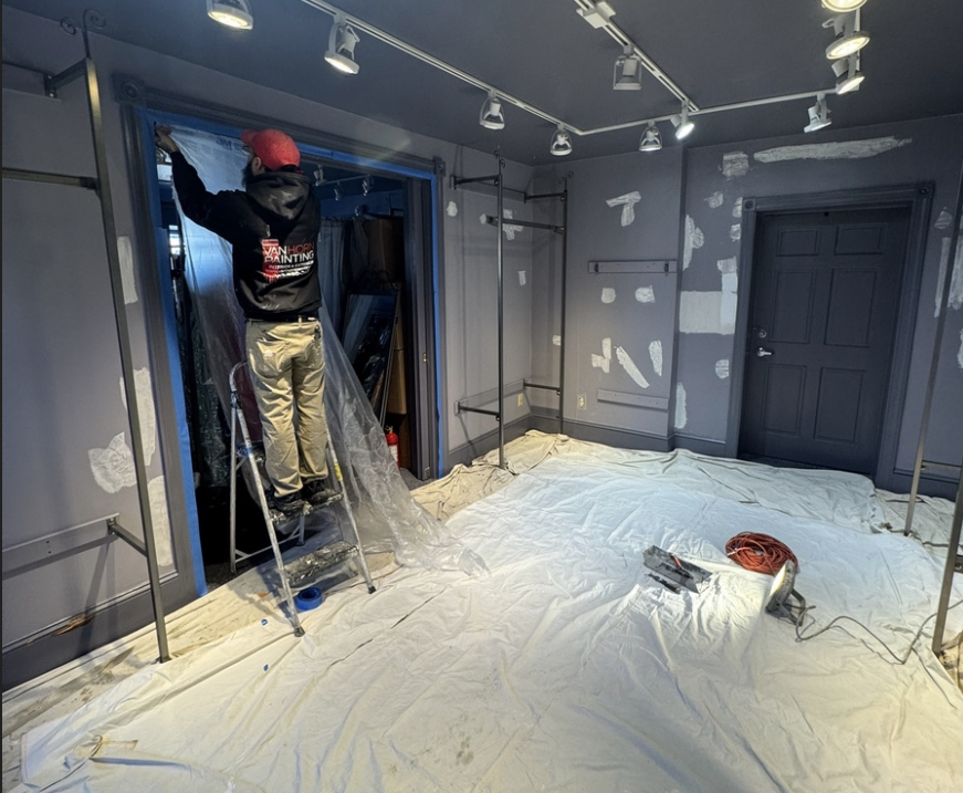 Professional painter with Van Horn Painting hoodie prepping a retail store for interior painting