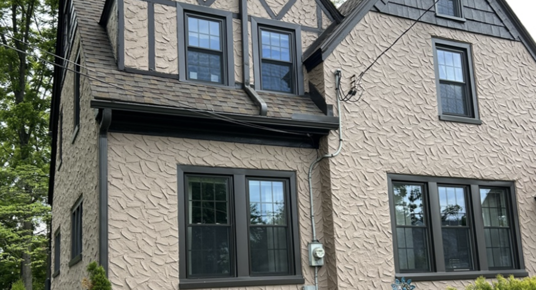 Tudor style home with beige textured stucco and dark brown trim