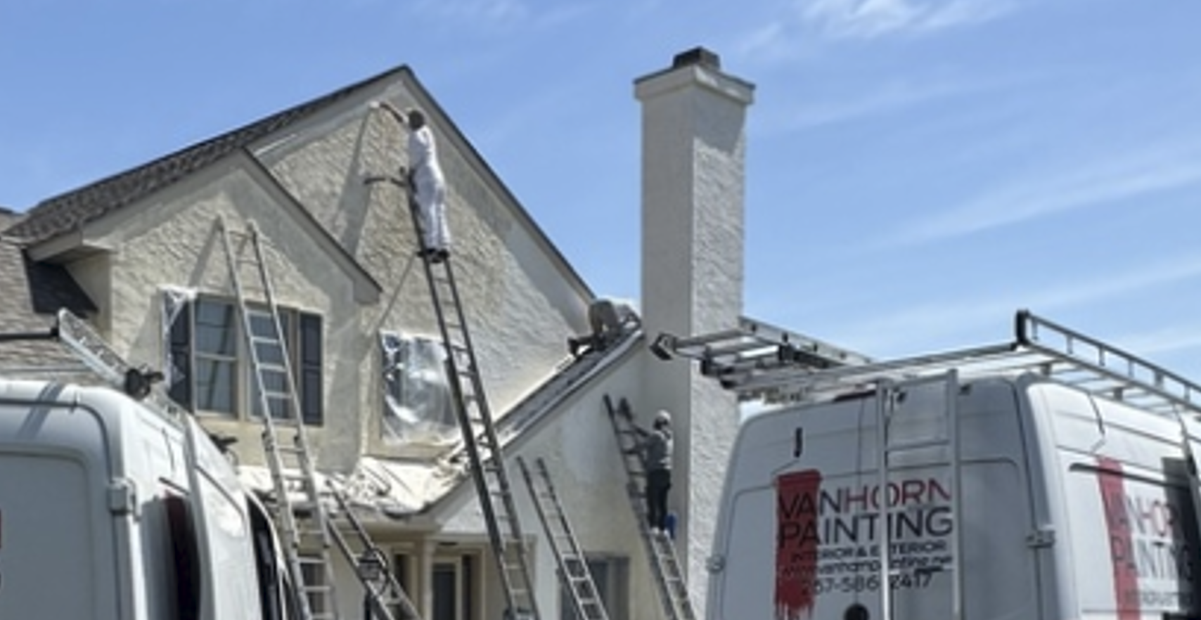 Van Horn Painting professionals on ladders painting a home's stucco facade in West Chester