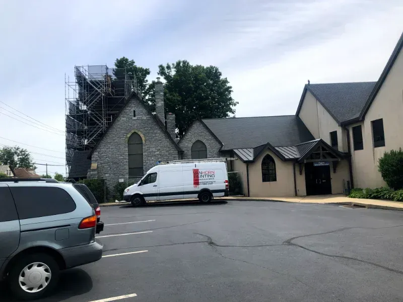 A white van is parked in front of a church.
