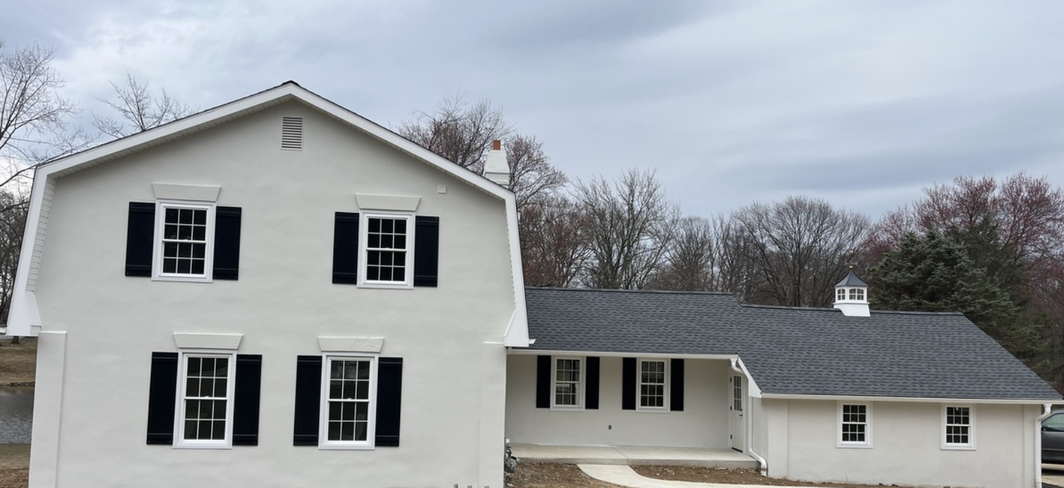 Split level home with white stucco and blue window shutters in Chester County