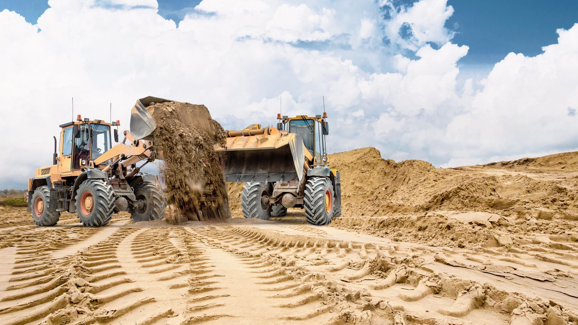 Construction hauling operation with wheel loaders moving and dumping large amounts of soil at a job site.]