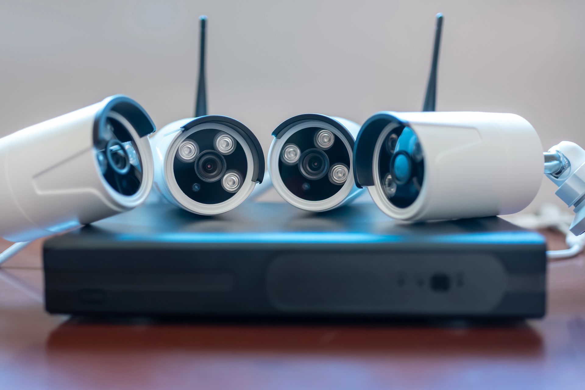 Cuatro cámaras de seguridad blancas y una unidad DVR negra sobre una superficie de madera.