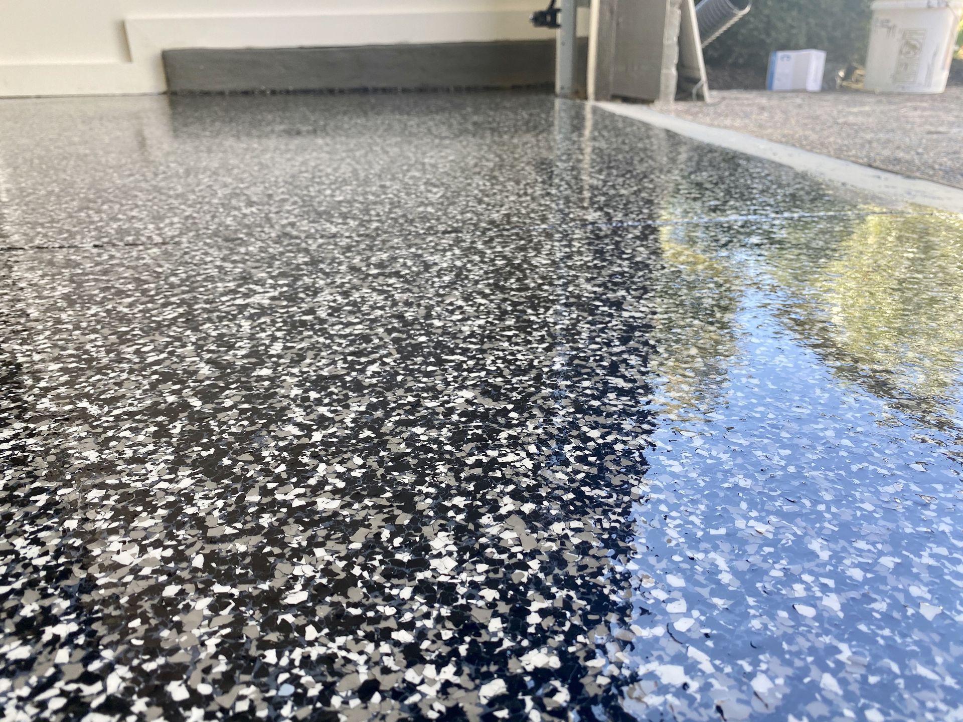 A close up of a black and white flake floor in a garage.