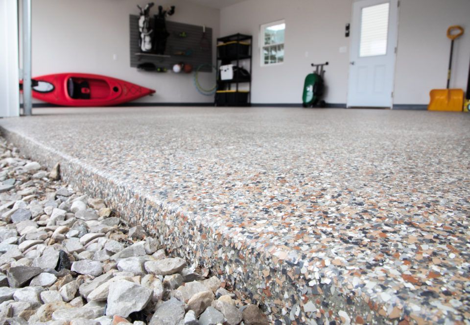 A garage with a kayak and a shovel on the floor.