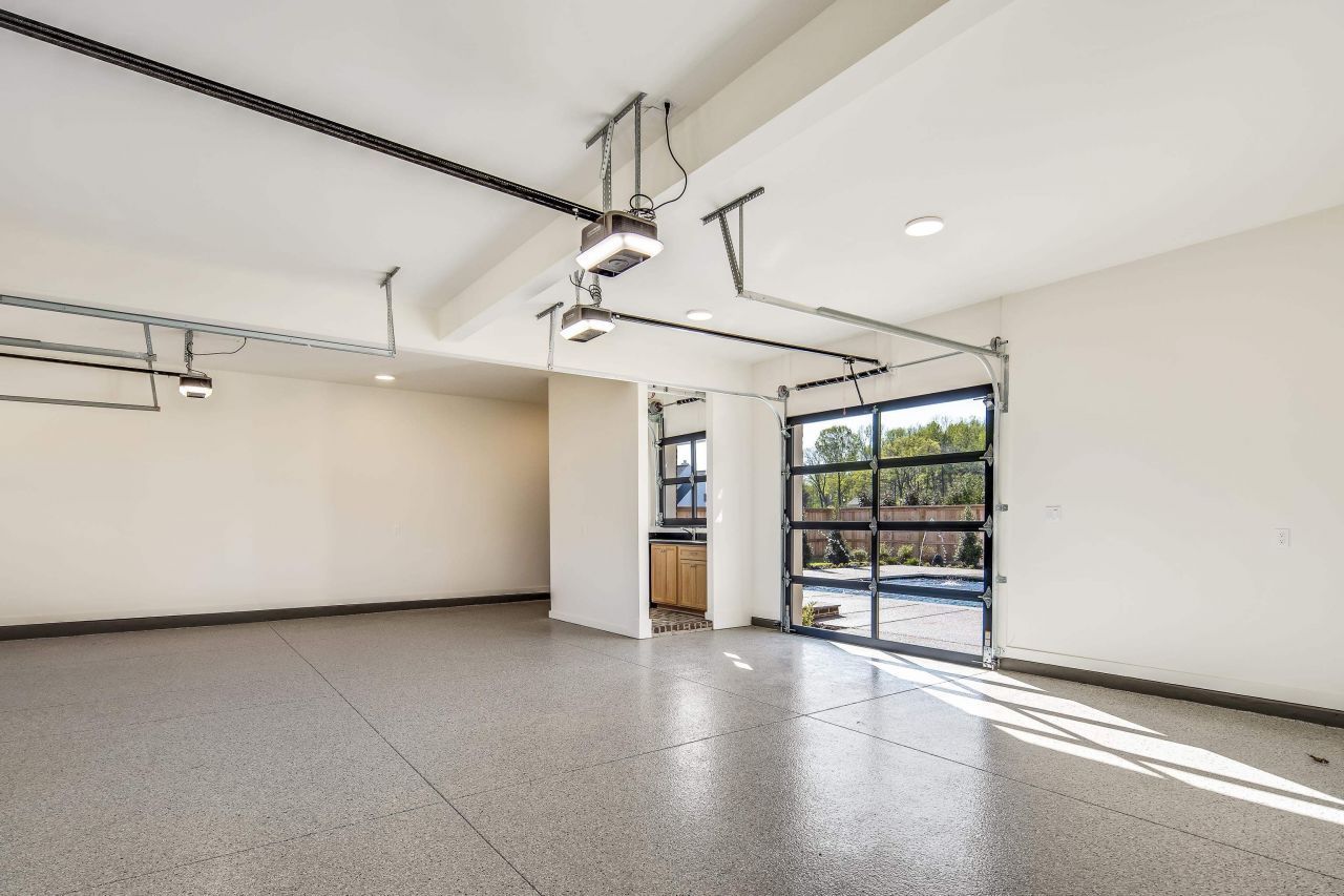 Empty garage with a speckled floor, glass garage door, and white walls.