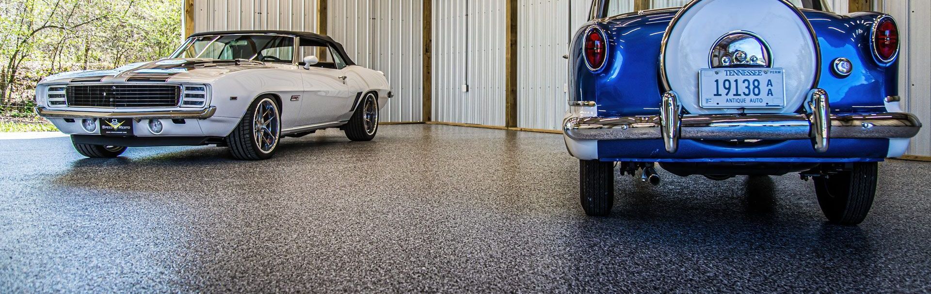 Two cars are parked next to each other in a garage.