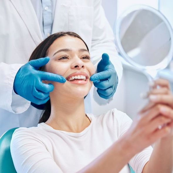 Woman Checking The Result Of Her Teeth in The Mirror - Beatrice, NE - Gleason Dental Clinic